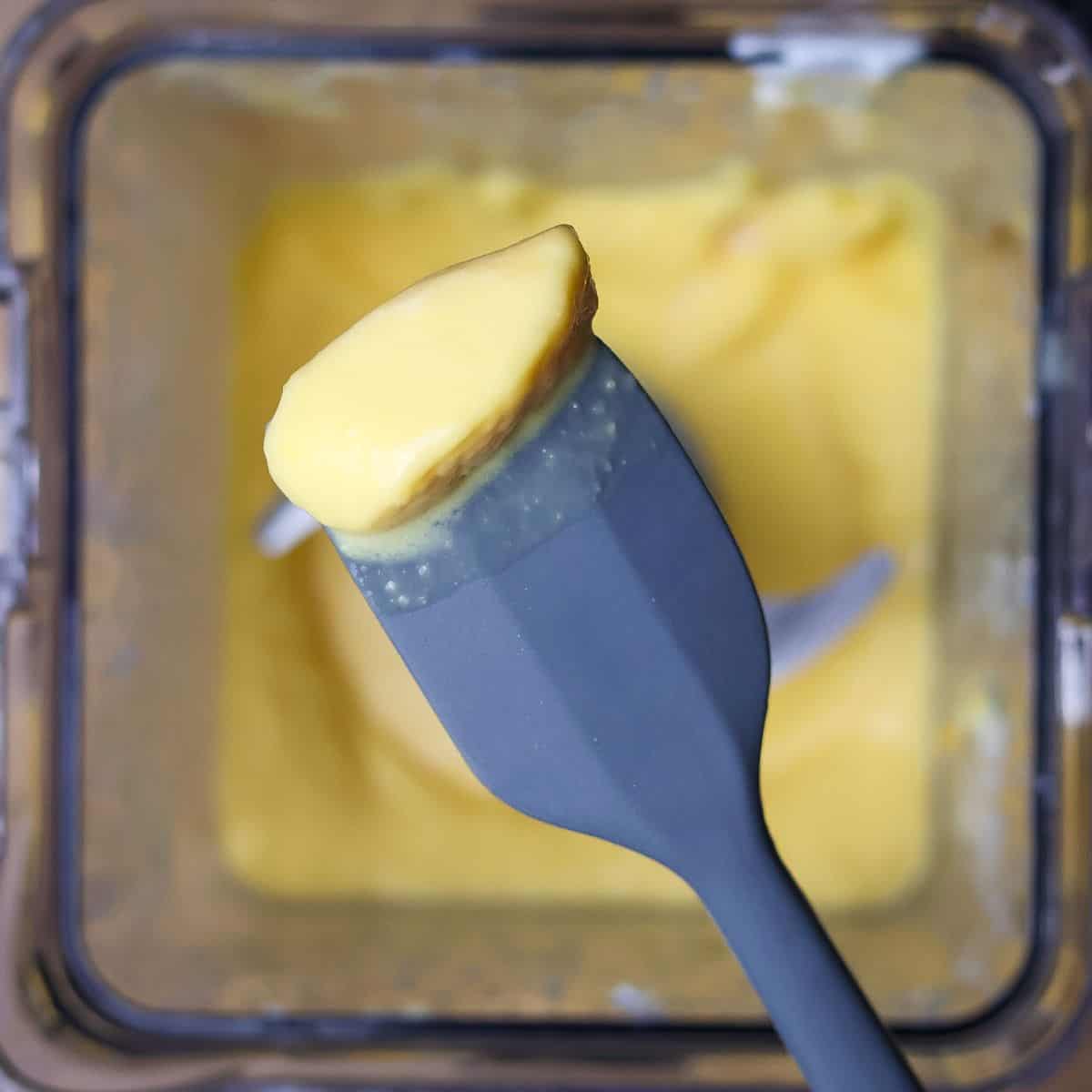 A spatula with a taste of mango smoothie indicating a taste test before adjusting flavors.