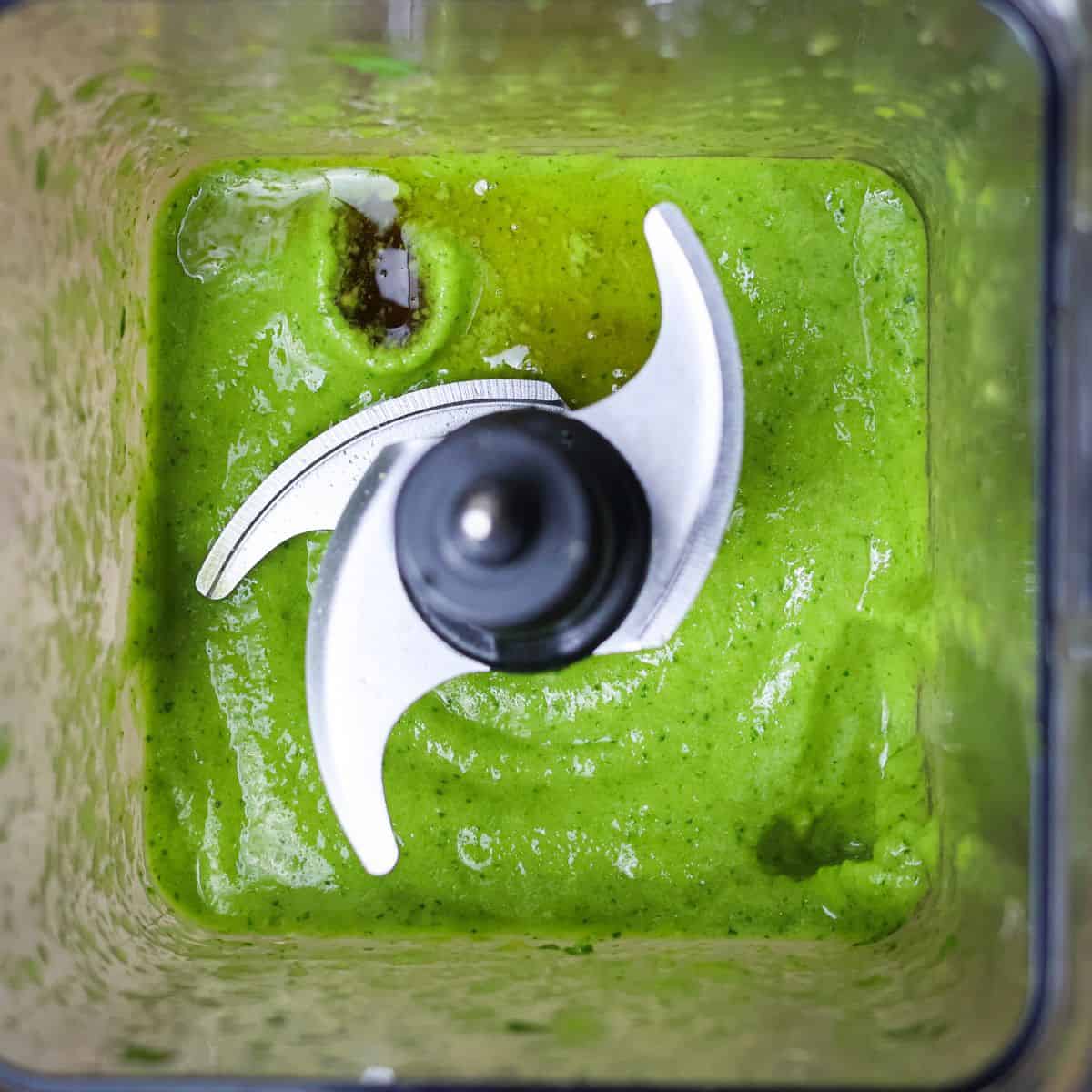 Top view of a blender showing a vibrant green smoothie mix with maple syrup added after a taste test.