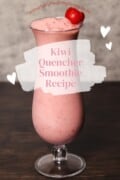 Promotional image featuring a tall glass filled with a freshly made Kiwi Quencher smoothie, topped with a ripe strawberry. In the background, there's a soft focus on a gray texture. The image has a bright, airy feel with floating white hearts and a torn paper graphic overlay. 'Kiwi Quencher Smoothie Recipe' is written in pink script, and the website 'mindfullyhealthyliving.com' is prominently displayed at the top, suggesting a refreshing and healthy recipe available on the blog.
