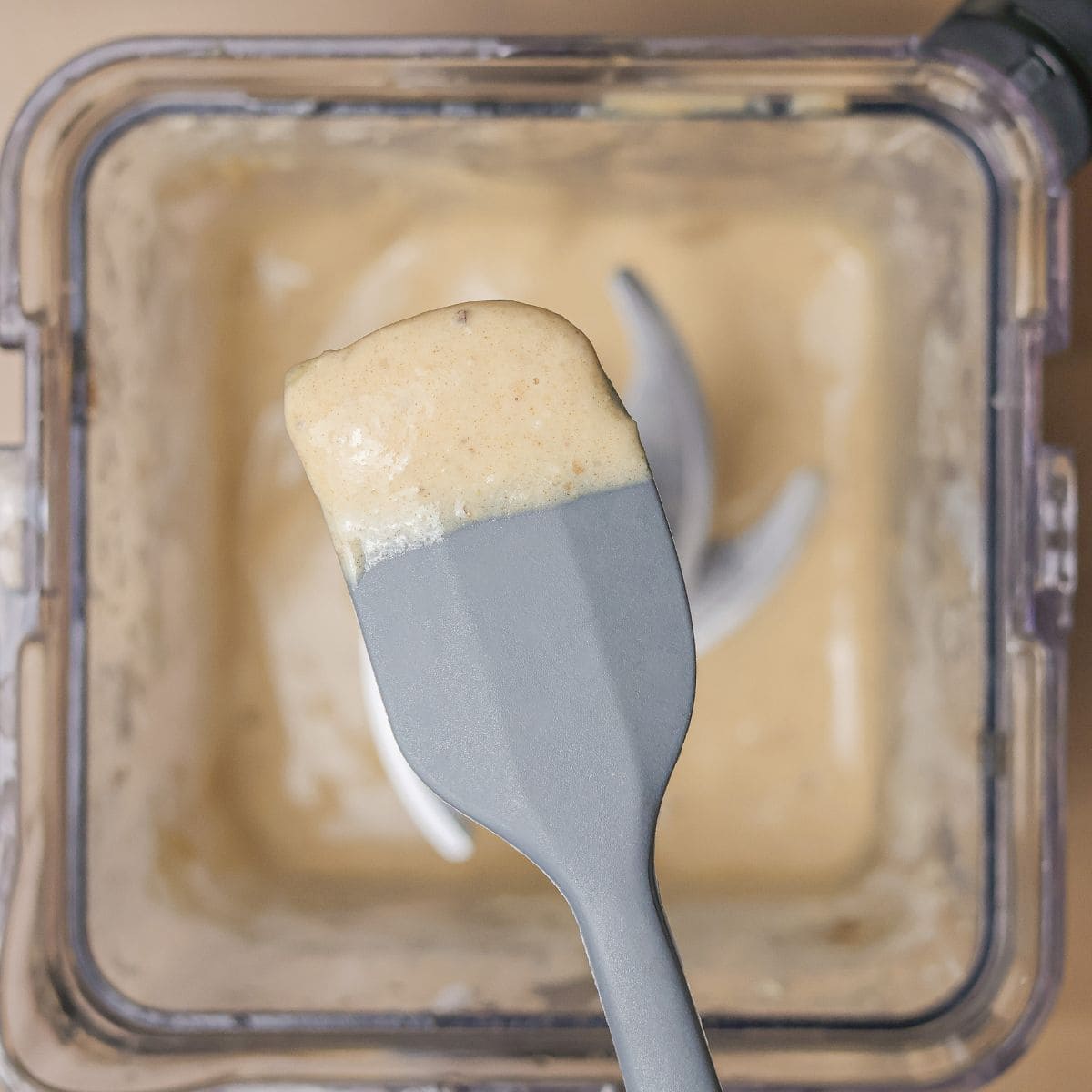 Top view of a spoon scooping up a sample from a freshly blended Hulk smoothie to test the flavor and texture.
