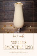 Promotional Pinterest graphic for a healthy version of The Hulk smoothie from Smoothie King, featuring a tall glass of creamy smoothie topped with chopped pecans on a wooden backdrop, with text overlay 'how to make The Hulk Smoothie King' at mindfullyhealthyliving.com.