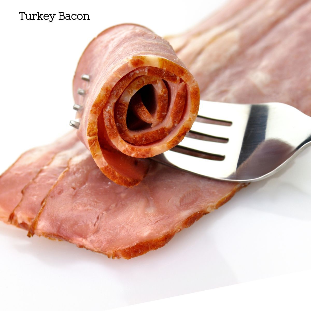 A stack of turkey bacon slices with one rolled up with a fork through it.