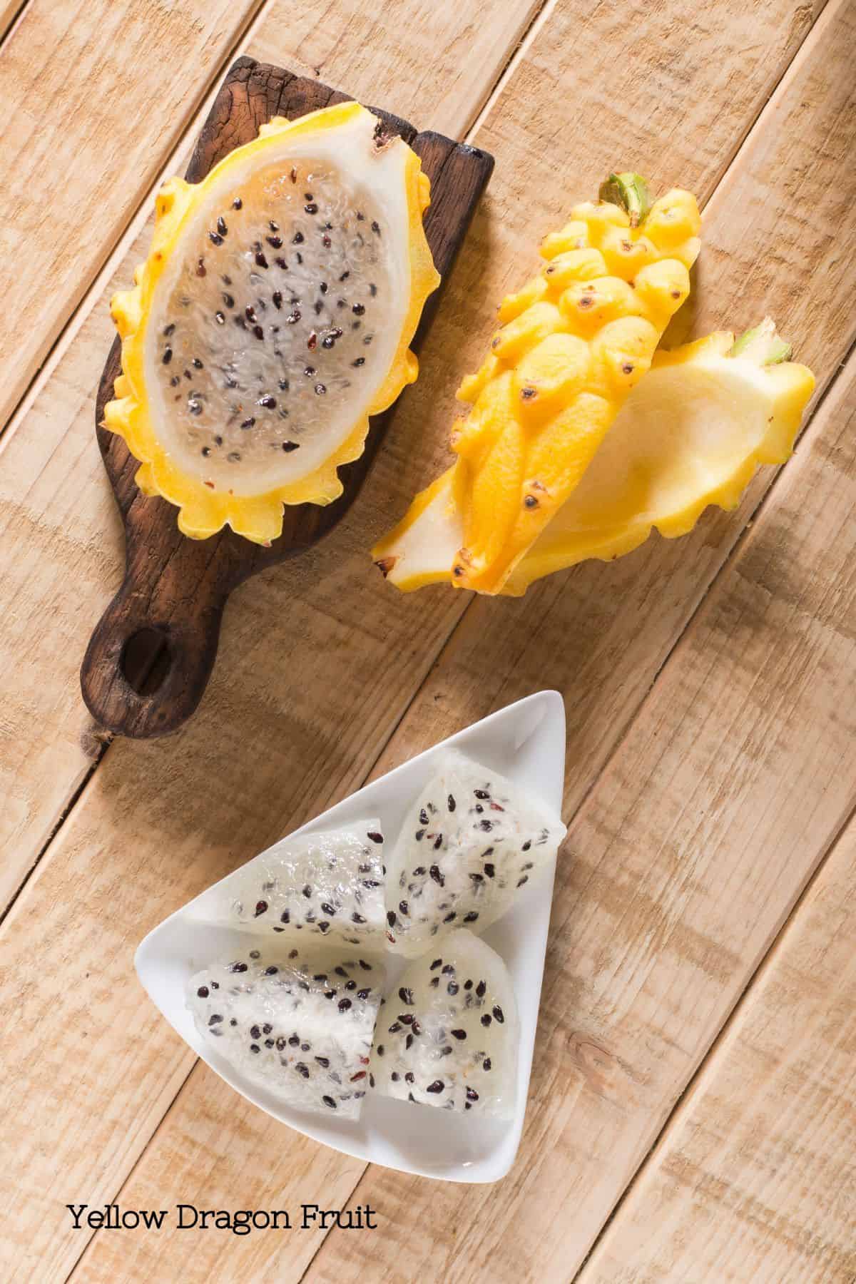 A bowl of yellow dragon fruit cut up with whit flesh and black seeds.