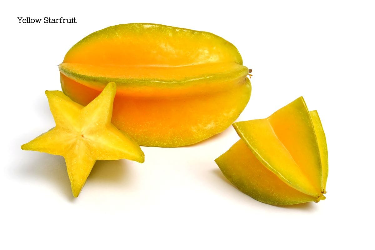 A full yellow starfruit next to a cut star fruit piece that is star-shaped.
