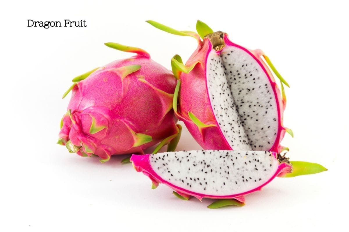 Red dragon fruit cut open to reveal a white flesh with black seeds.
