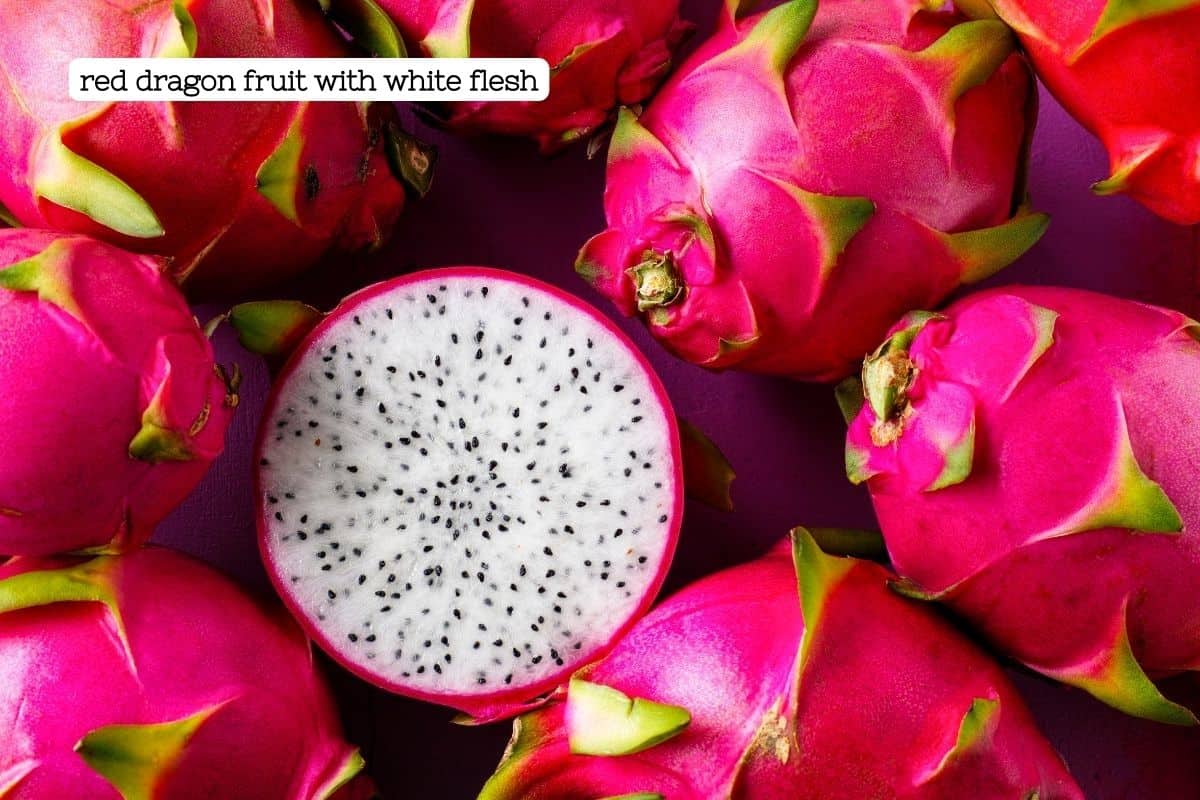 Bright pink dragon fruit with one cut open to reveal a white center with black seeds.