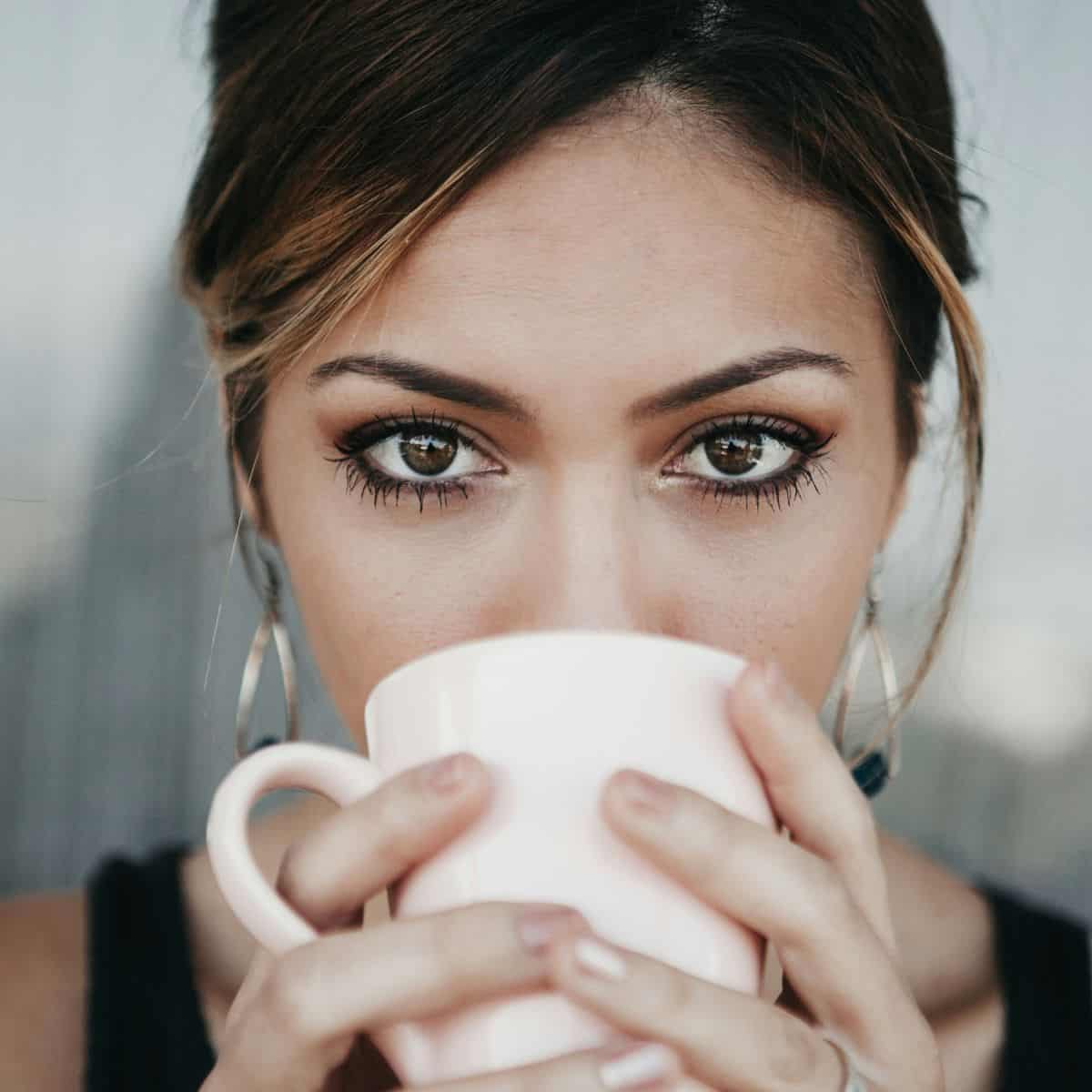 A woman drinking from a coffee cup.