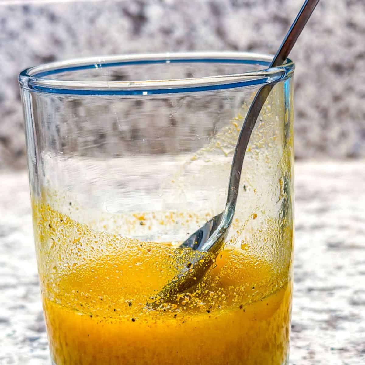 A spoon stirring the ingredients for turmeric lemon juice mixture.