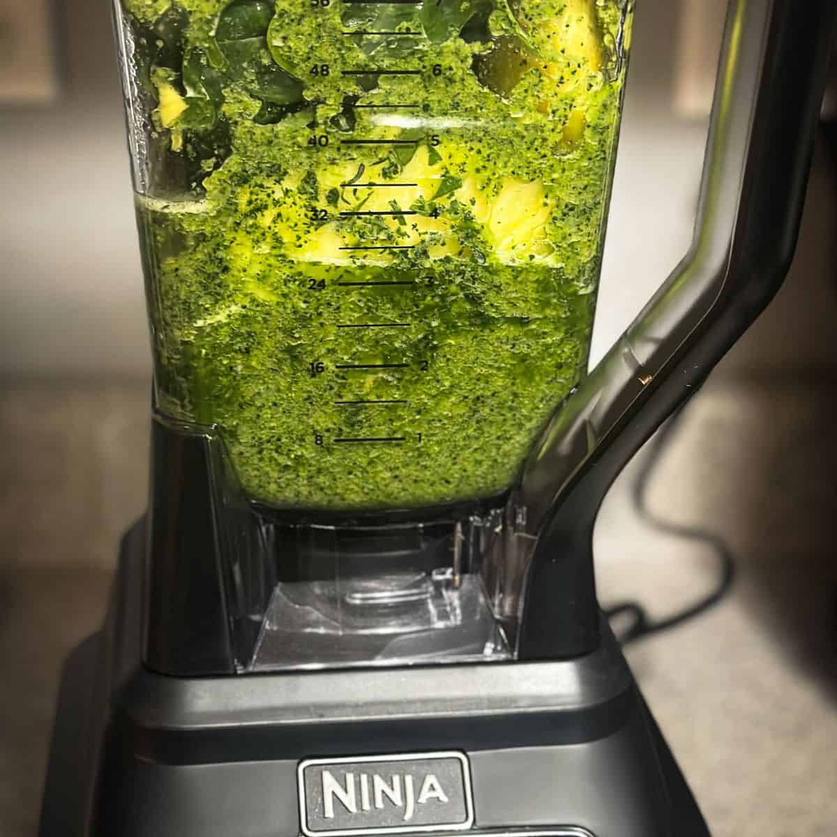 A smoothie in a blender partially blended, ready to scrape down the sides and blend again.