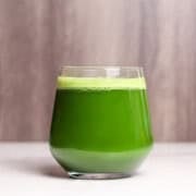A glass of green juice with light foam at the top.