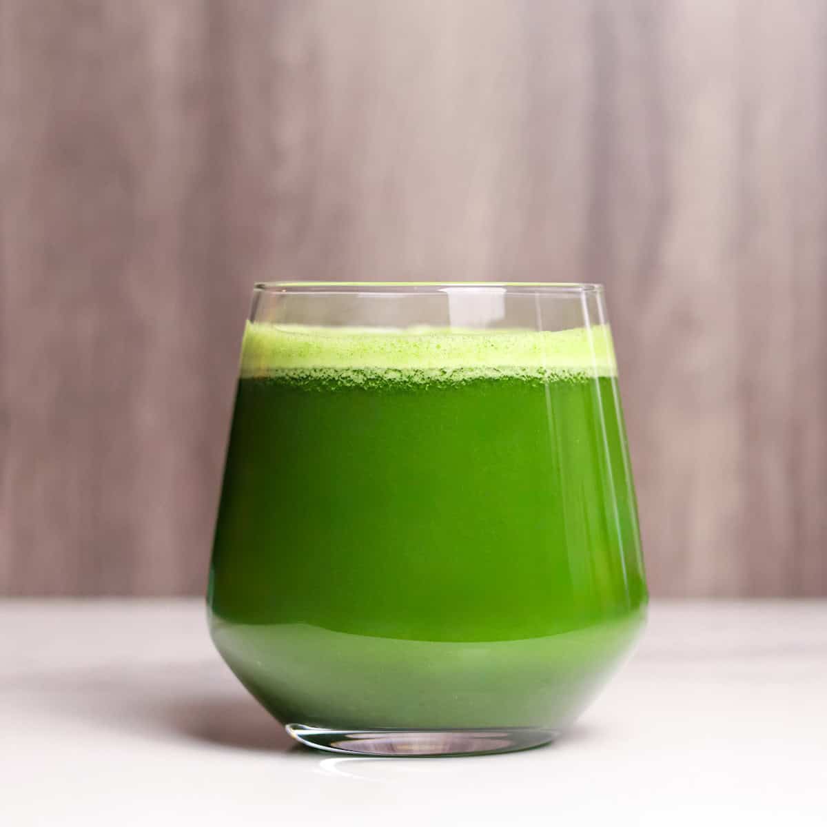 A glass of green juice with light foam at the top.