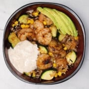 A Cajun Shrimp and Rice Bowl topped with yogurt sauce and avocado slices.