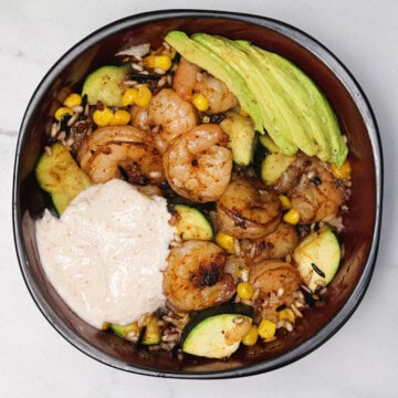 A Cajun Shrimp and Rice Bowl topped with yogurt sauce and avocado slices.