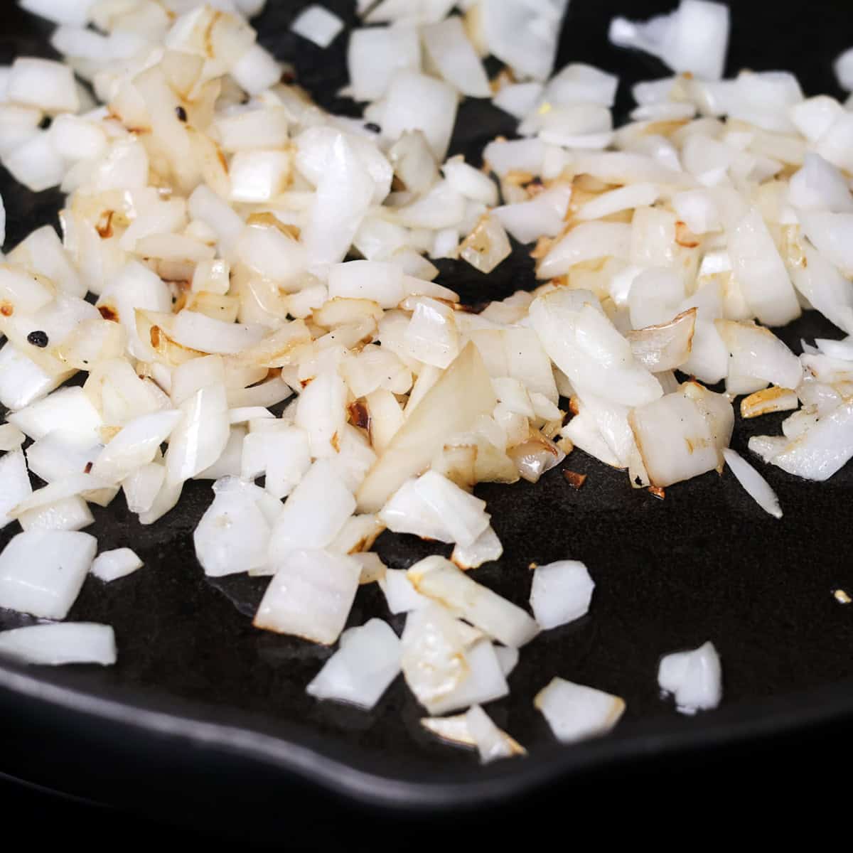 Chopped onion and garlic sauteeing in a skillet.