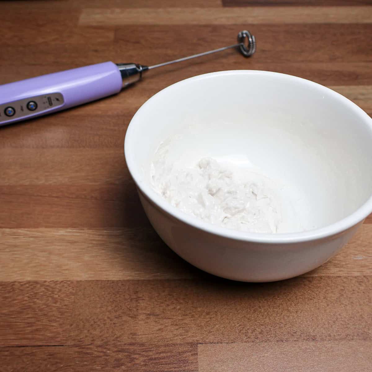 Coconut cream in a bowl ready to be frothed with an electric frother.