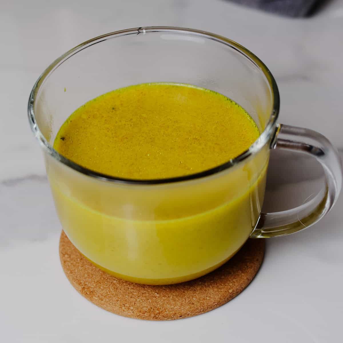 Warm golden milk poured into a mug ready for coconut cream.