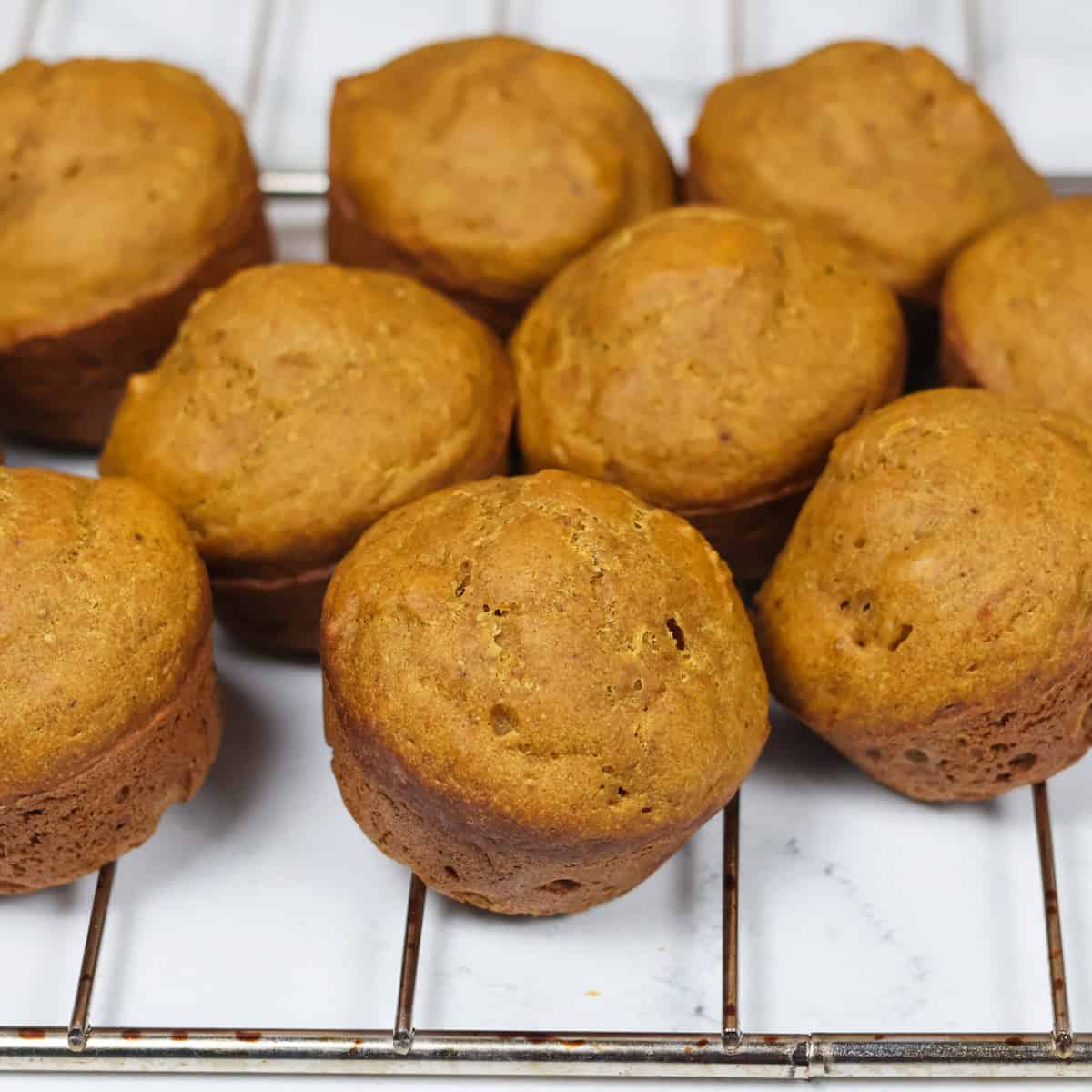 Pumpkin muffins cooling on a wire rack.