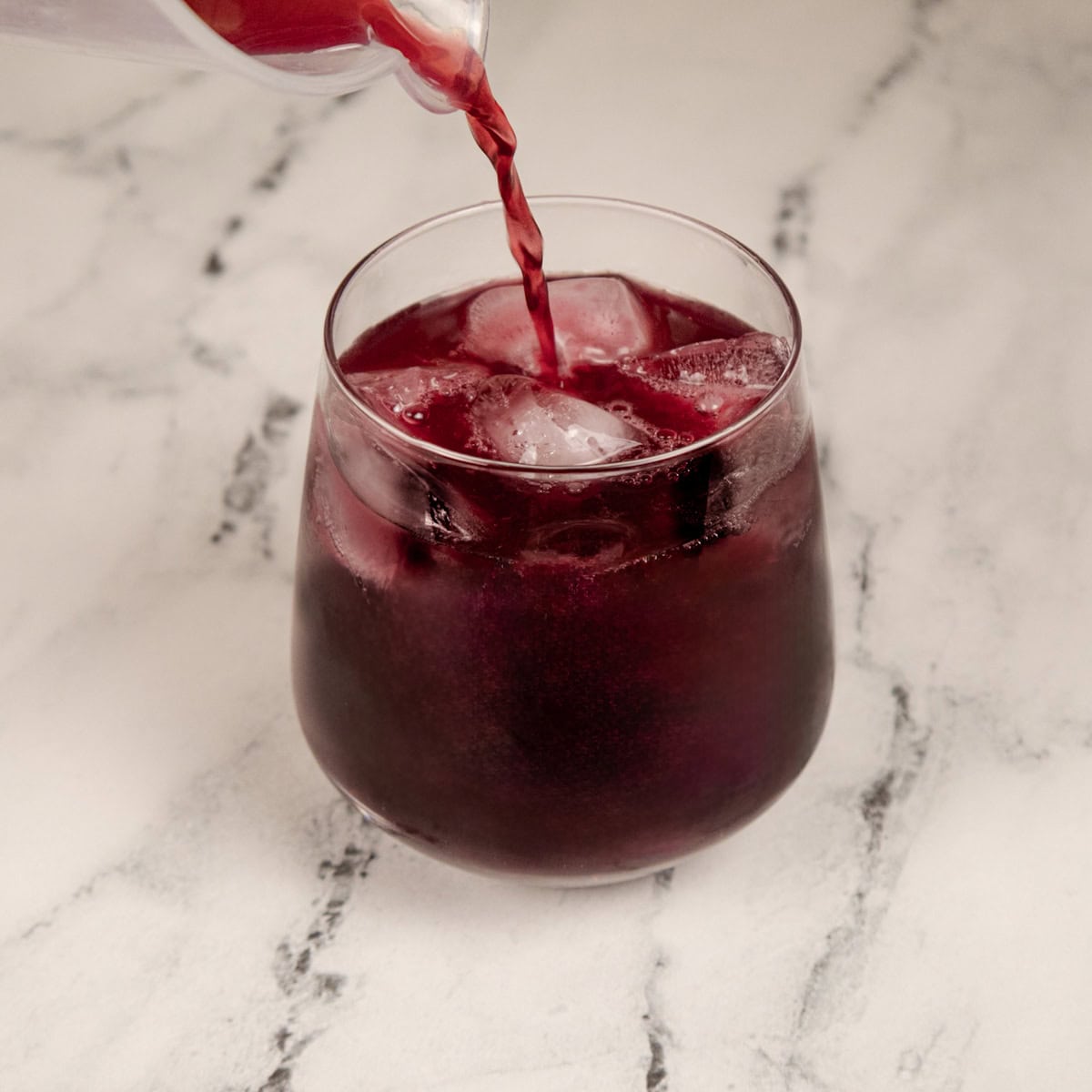 Pouring Adrenal Cocktail Juice over ice.