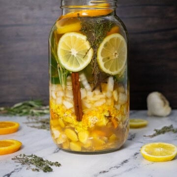 A decorative photo of fire cider ingredients and vinegar in the jar ready for infusion.