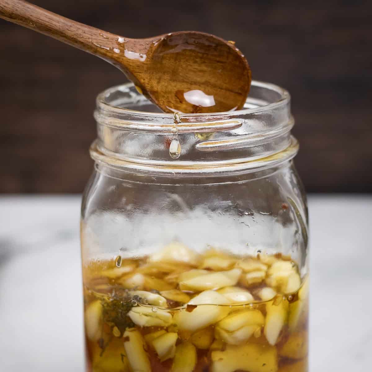 A wooden spoon stirring garlic honey ferment.