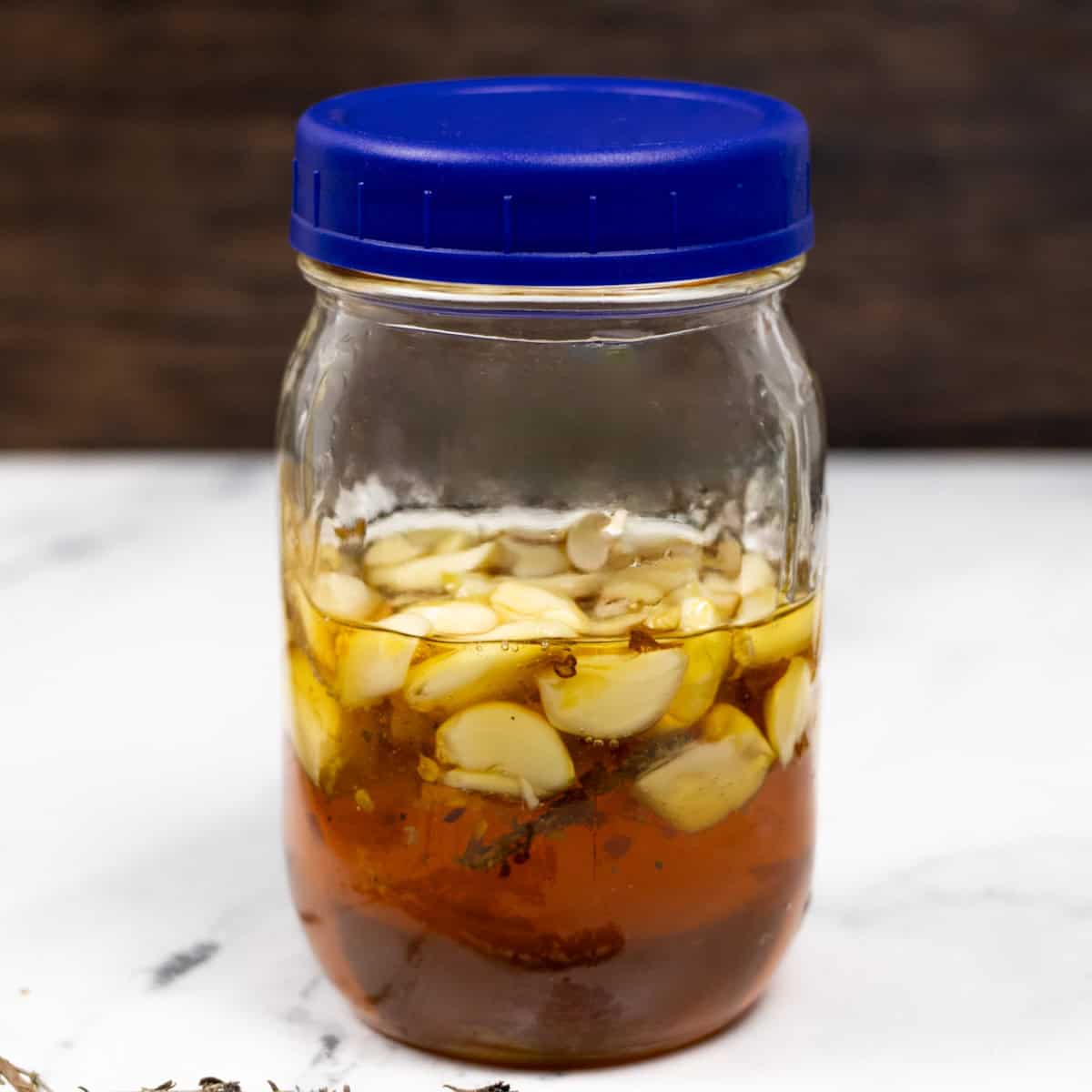 A jar of honey garlic ferment with a blue lid loosely screwed on.