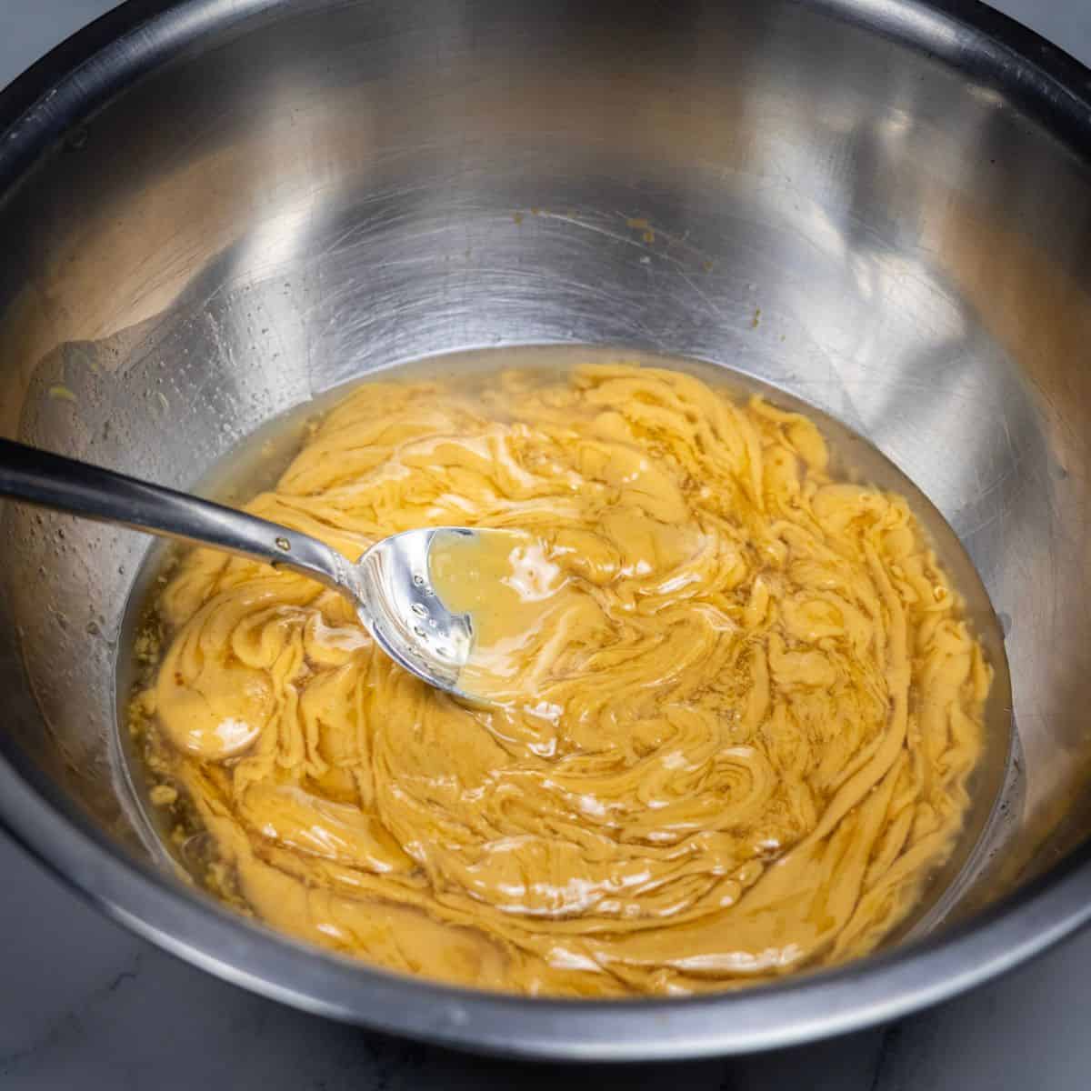 Peanut butter, oil, salt, vanilla, and maple mixed together in a bowl.