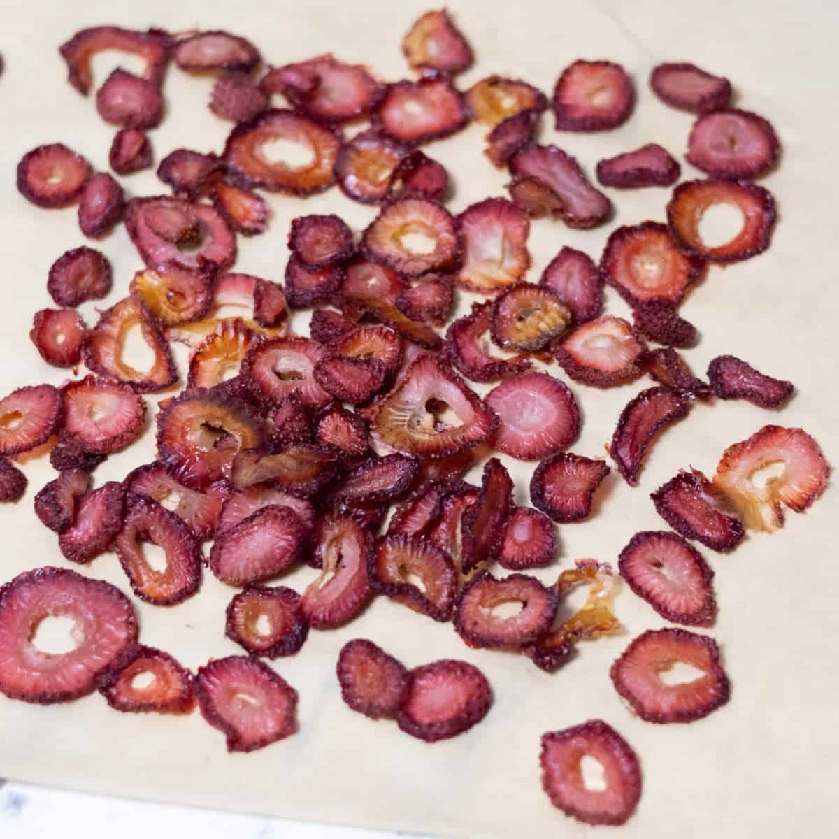 Dried strawberry slices cooling on parchment paper.
